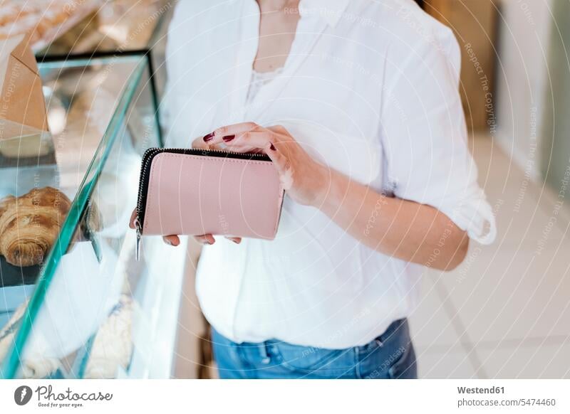 Female customer holding wallet at checkout counter in bakery color image colour image indoors indoor shot indoor shots interior interior view Interiors day