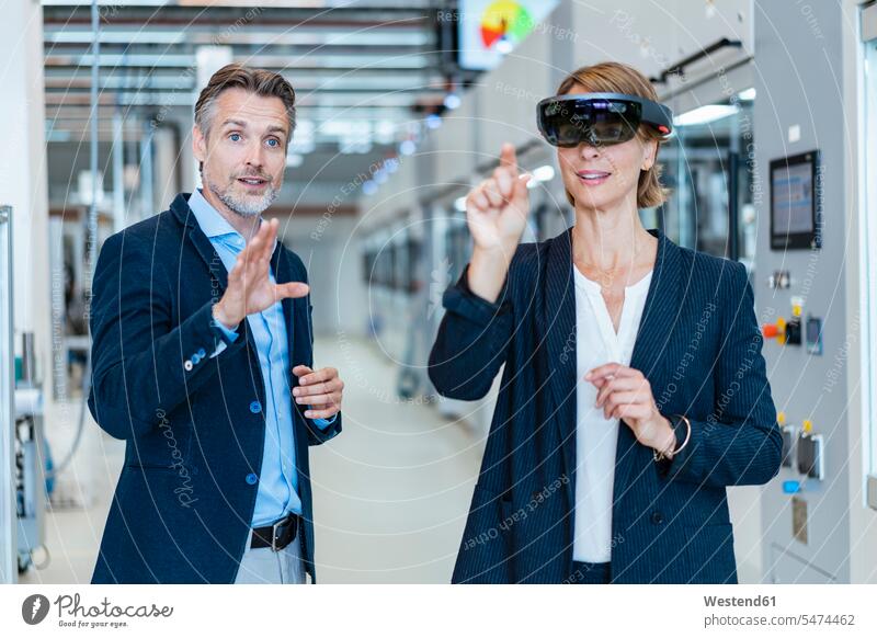 Businesswoman with AR glasses and businessman in a modern factory human human being human beings humans person persons caucasian appearance caucasian ethnicity