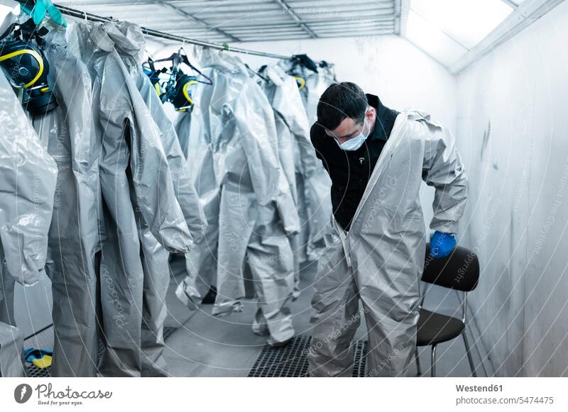 Healthcare worker wearing protective suit in locker room color image colour image Corona Virus Coronavirus disease Covid-19 COVID19 COVID 19 pandemic