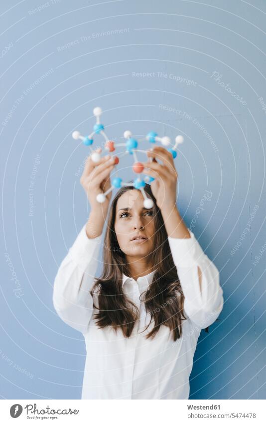 Female scientist holding molecule model, looking for solutions woman females women molecular model female scientists Solutions Adults grown-ups grownups adult