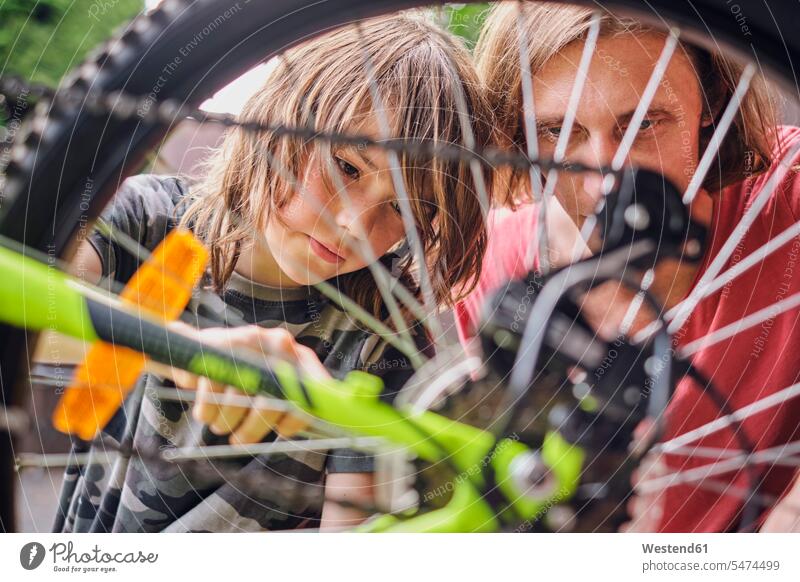 Father and son repairing bicycle during sunny day color image colour image outdoors location shots outdoor shot outdoor shots daylight shot daylight shots