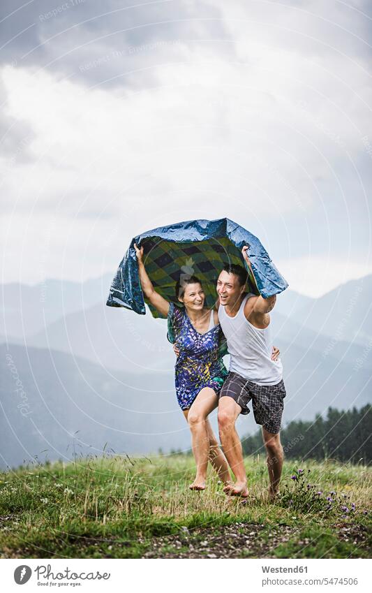 Happy couple running on a meadow in the mountains in rain, Achenkirch, Austria Blankets relax relaxing delight enjoyment Pleasant pleasure Cheerfulness