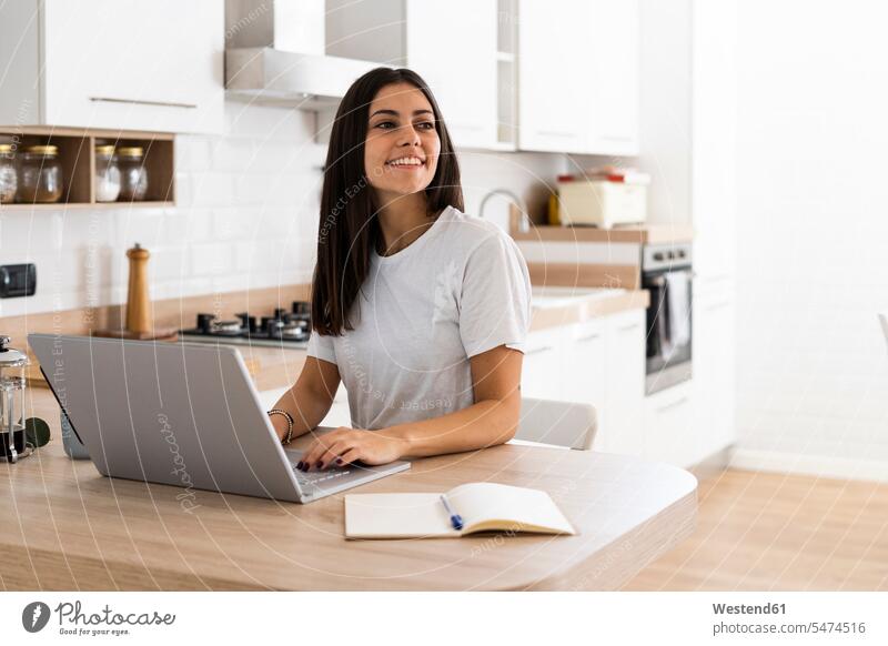 Smiling young woman using laptop at home human human being human beings humans person persons celibate celibates singles solitary people solitary person