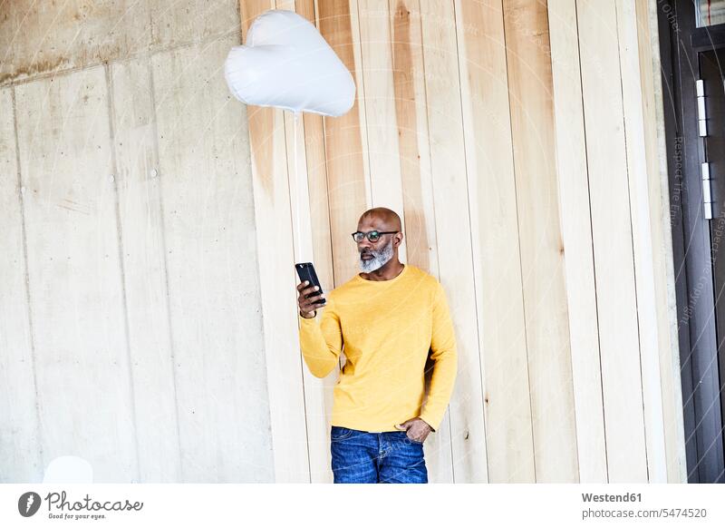 Mature businessman holding cell phone attached to cloud balloon clouds mobile phone mobiles mobile phones Cellphone cell phones balloons Attached Businessman