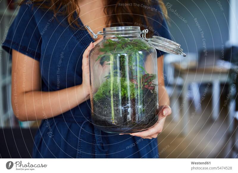 Close-up of woman holding terrarium in glass jar at home color image colour image indoors indoor shot indoor shots interior interior view Interiors day