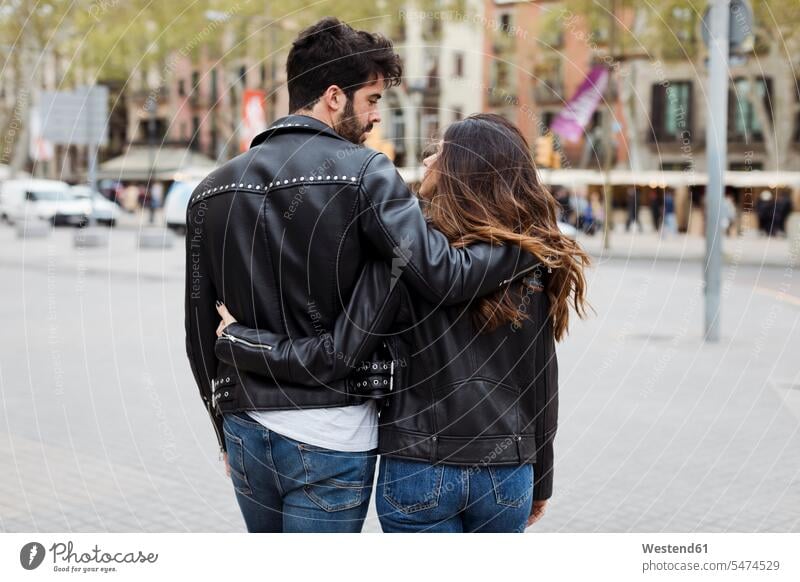 Spain, Barcelona, young couple embracing and walking in the city embrace Embracement hug hugging town cities towns twosomes partnership couples going outdoors