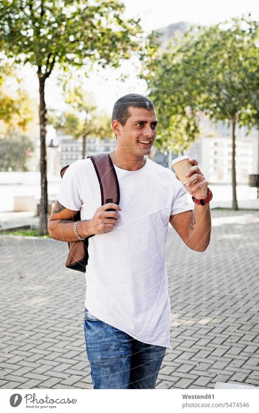 Smiling young man with takeaway coffee on the go smiling smile men males Coffee on the move on the way on the road Adults grown-ups grownups adult people