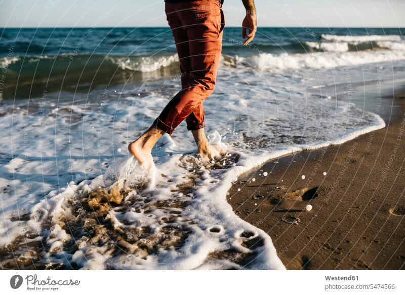 Rear view of man with orange trousers walking on a beach at water's edge human human being human beings humans person persons caucasian appearance