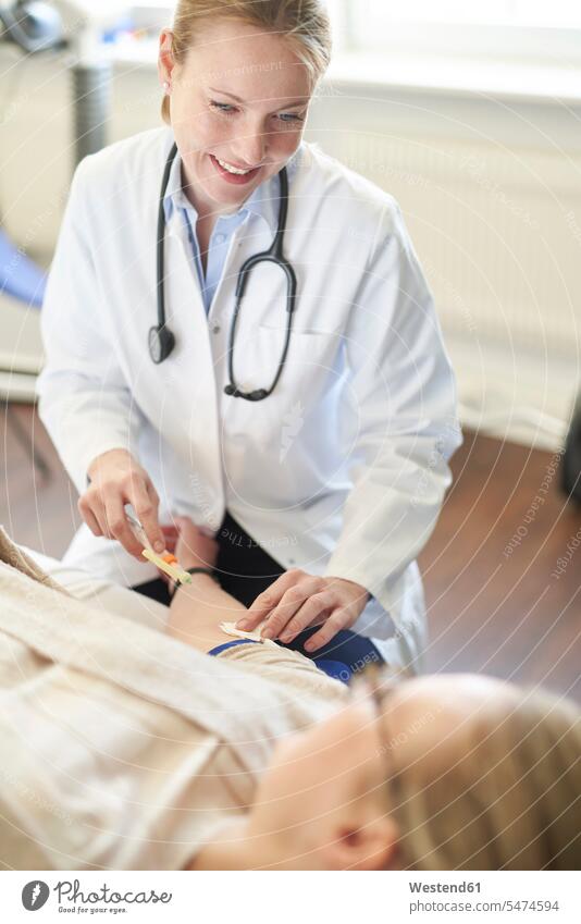 Female doctor taking a blood sample from patient in medical practice arm arms patients Germany Dedication Engagement dedicated Eager Input eagerness Commitment