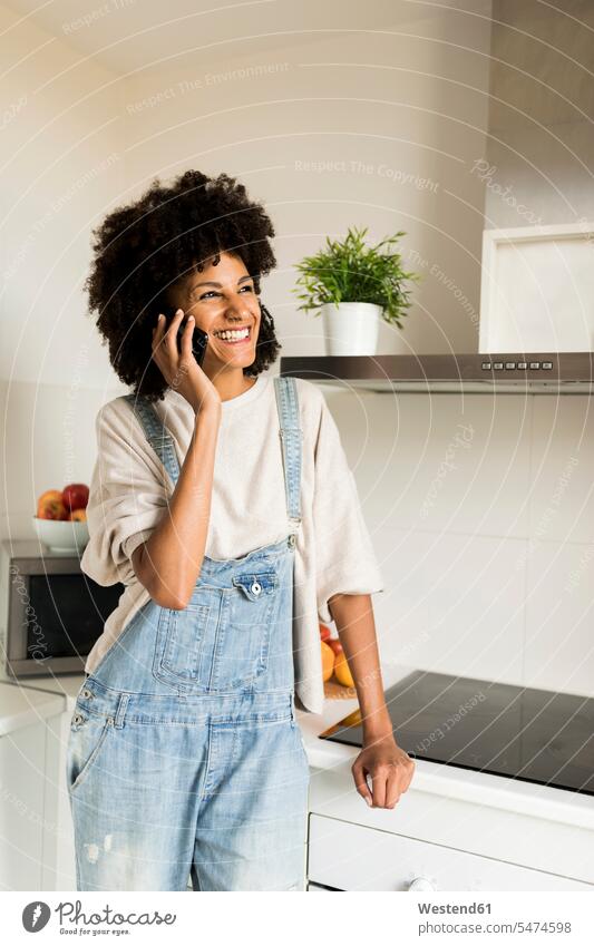 Happy woman on cell phone in kitchen at home mobile phone mobiles mobile phones Cellphone cell phones females women happiness happy on the phone call