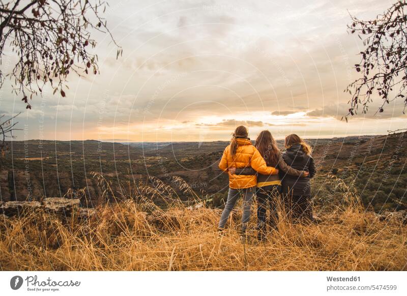 Spain, Alquezar, three friends embracing on a hill overlooking the scenery woman females women Hill hilly Hills embrace Embracement hug hugging sunset sunsets