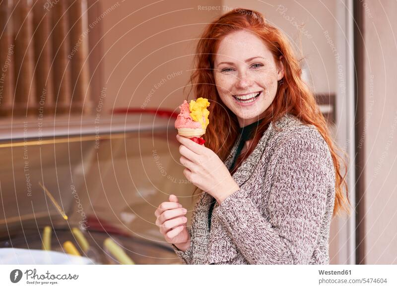 Portrait of happy redheaded woman with ice cream cone females women icecream Ice Creams ice-cream red hair red hairs red-haired happiness portrait portraits