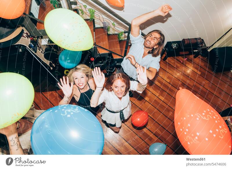 Male and female friends dancing with colorful balloons during party at home color image colour image indoors indoor shot indoor shots interior interior view