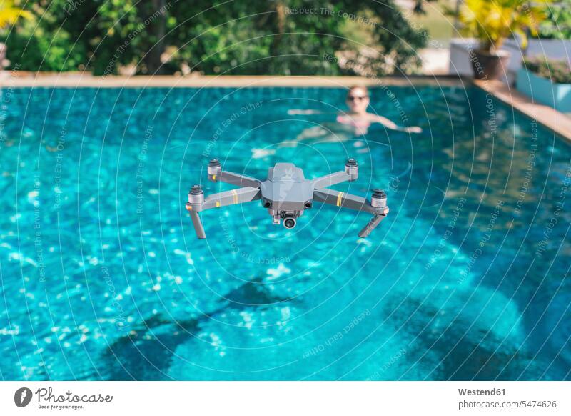 Flying drone over the swimming pool technology technologies engineering copy space mid-air midair mid air hovering floating pools swimming pools woman females