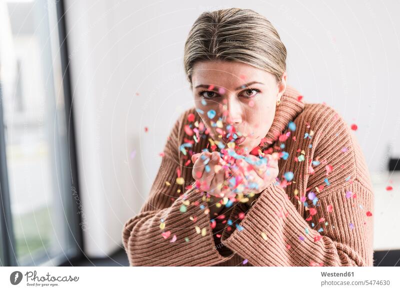Portrait of young woman blowing confetti in the air portrait portraits females women paper Adults grown-ups grownups adult people persons human being humans