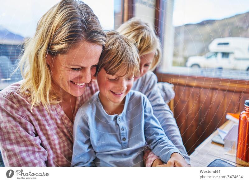 Happy mother with two sons sitting at table in a cafe manchild manchildren Table Tables mommy mothers mummy mama Seated happiness happy boy boys males family