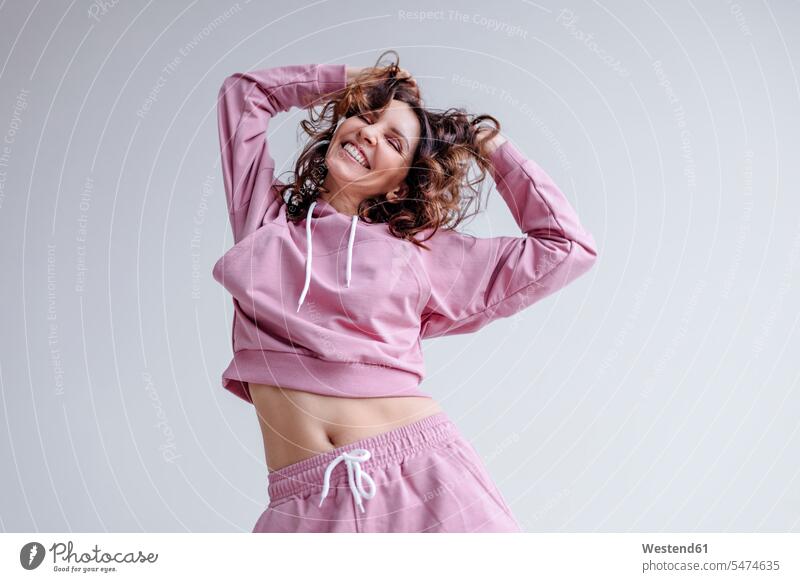 Smiling woman wearing pink track suit with hands in hair human human being human beings humans person persons caucasian appearance caucasian ethnicity european
