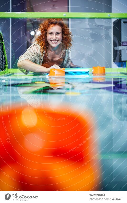 Happy woman playing air hockey and having fun in an amusement arcade human human being human beings humans person persons caucasian appearance