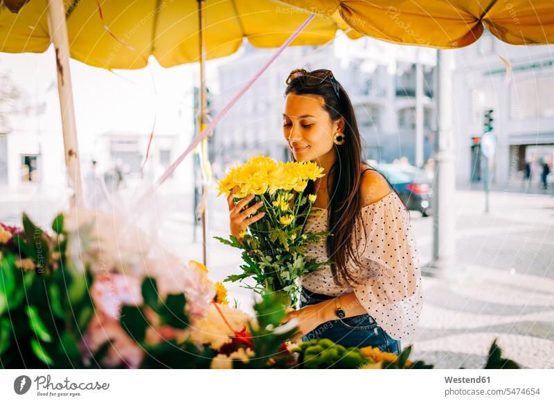 Young woman smelling bouquet of flowers at flower shop color image colour image outdoors location shots outdoor shot outdoor shots day daylight shot