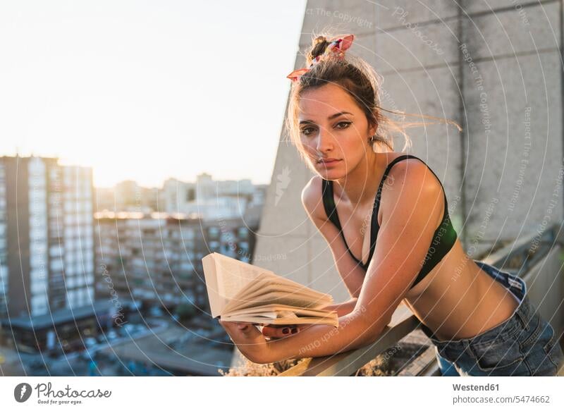 Portrait of young woman wearing bra reading book on balcony portrait portraits books Brassiere bras balconies females women lingerie underwear Adults grown-ups
