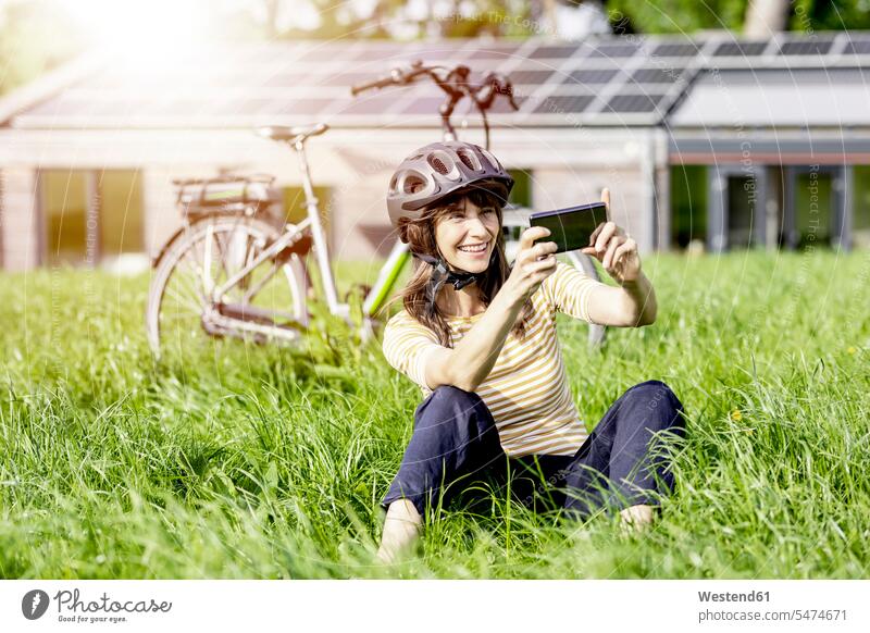 Happy woman sitting on a meadow with bicycle taking a selfie human human being human beings humans person persons caucasian appearance caucasian ethnicity