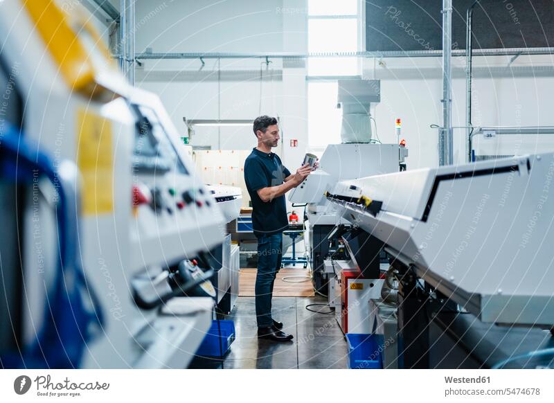 Mature male technician examining machine part while standing in industry color image colour image indoors indoor shot indoor shots interior interior view