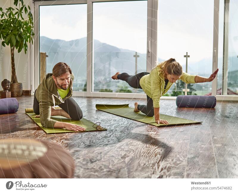 Couple practicing yoga in a room with panorama window windows couple twosomes partnership couples practice practise exercise exercising practising mindfulness