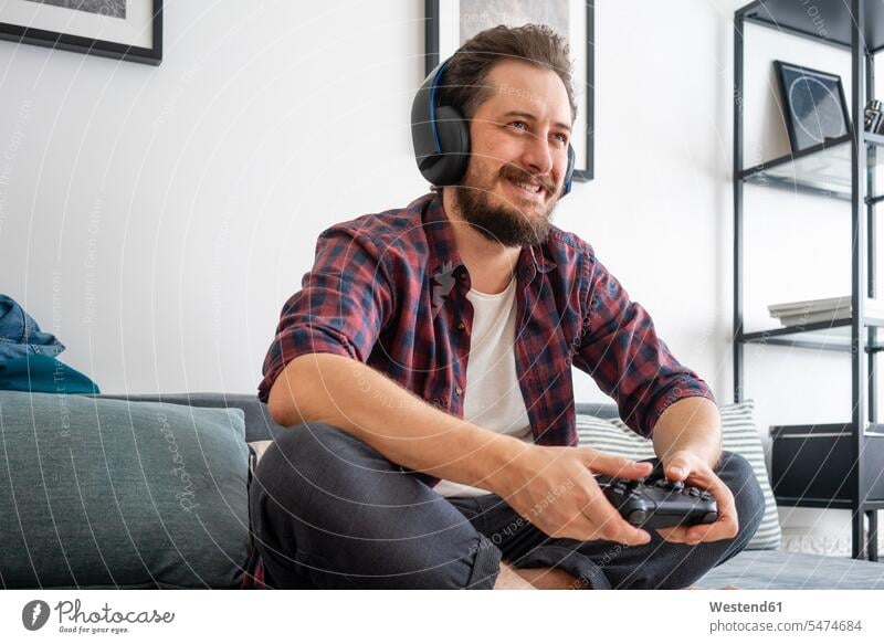 Man sitting on couch and playing video game human human being human beings humans person persons caucasian appearance caucasian ethnicity european 1