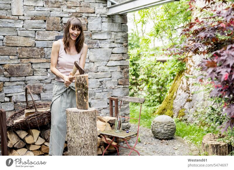 Screaming woman chopping wood in front of a house human human being human beings humans person persons caucasian appearance caucasian ethnicity european 1