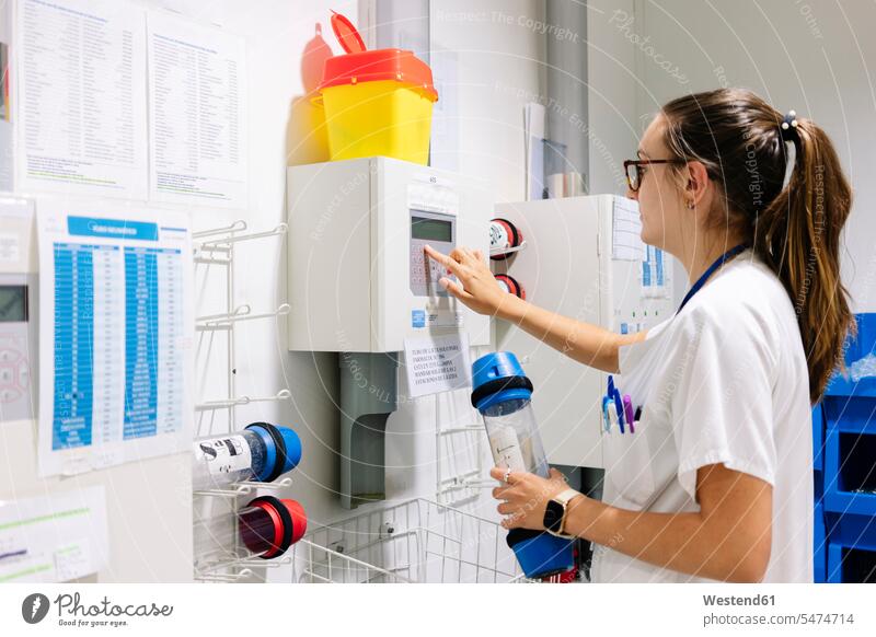 Female doctor using pneumatic tube system while standing in hospital color image colour image Spain indoors indoor shot indoor shots interior interior view