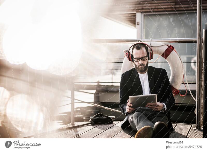 Hip businessman working on a houseboat, using headphones and digital tablet hip trendy Businessman Business man Businessmen Business men house boat house boats