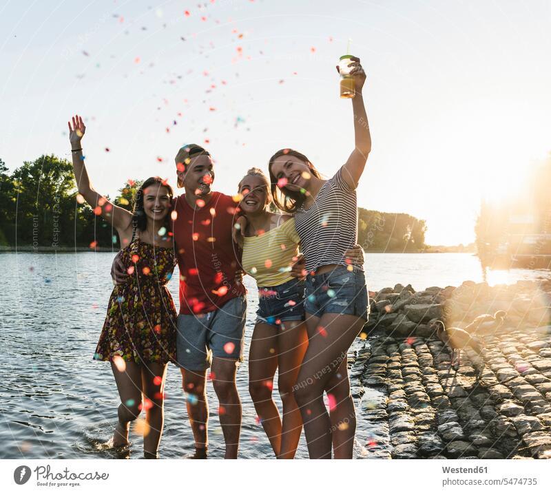 Confetti around group of happy friends having fun in a river at sunset Fun funny sunsets sundown happiness River Rivers group of people Group groups of people