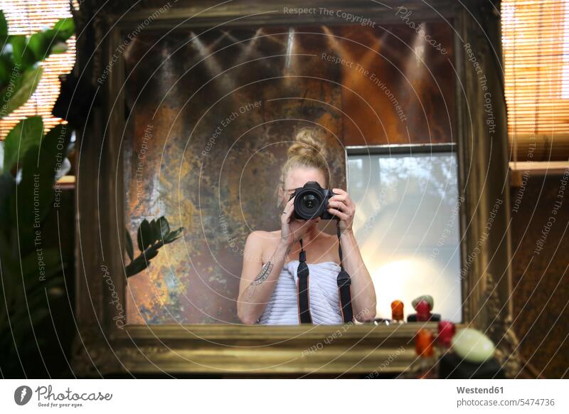 Mirror image of woman taking selfie with camera in bathroom Selfie Selfies females women cameras Domestic Bathroom bath room photographing mirror image