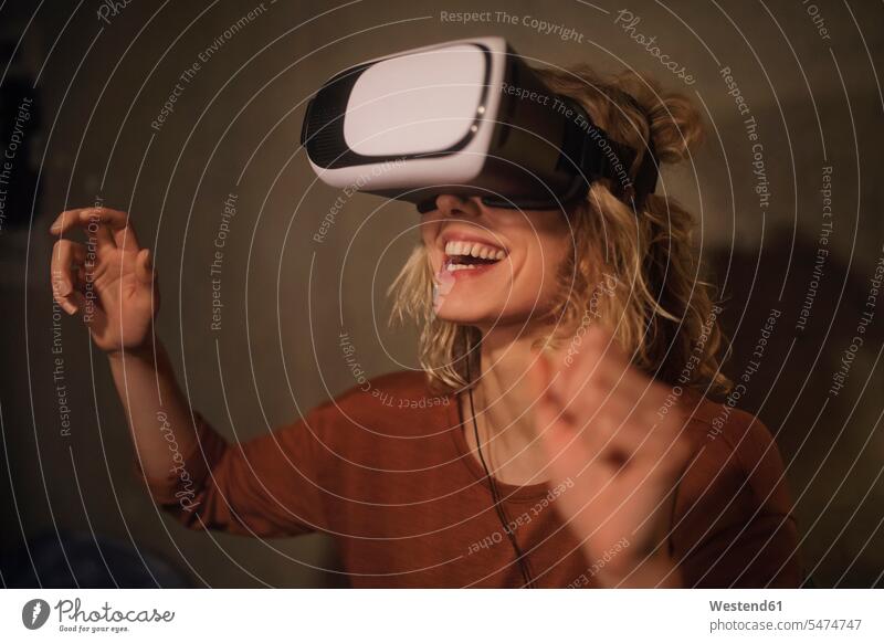 Laughing young woman using Virtual Reality Glasses at home discover discovering look seeing view viewing Ardor Ardour enthusiasm enthusiastic excited relax