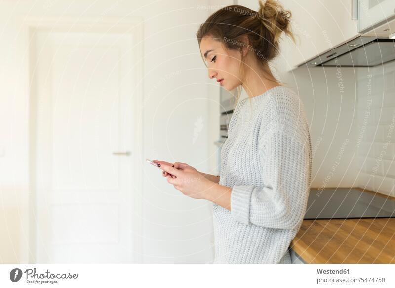 Young woman using smartphone at home jumper sweater Sweaters telecommunication phones telephone telephones cell phone cell phones Cellphone mobile mobile phones