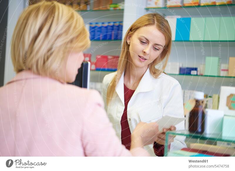 Portrait of pharmacist advising woman in pharmacy chemists counseling advise Apothecary drugstores pharmacies portrait portraits females women