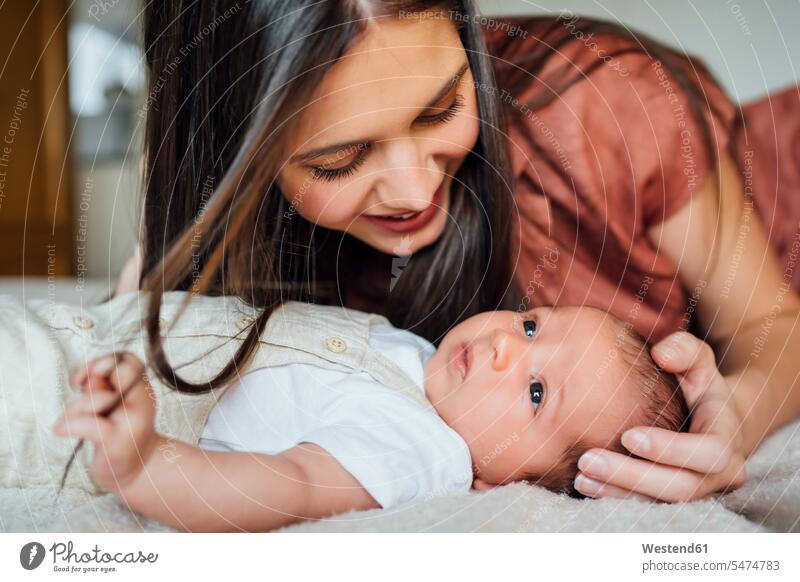 Happy mother looking at baby boy lying on bed color image colour image indoors indoor shot indoor shots interior interior view Interiors day daylight shot