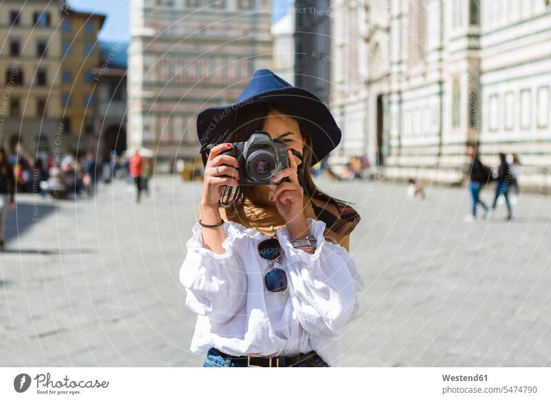 Italy, Florence, Piazza del Duomo, young tourist taking photo with camera photograph photographs photos woman females women female tourist cameras image images
