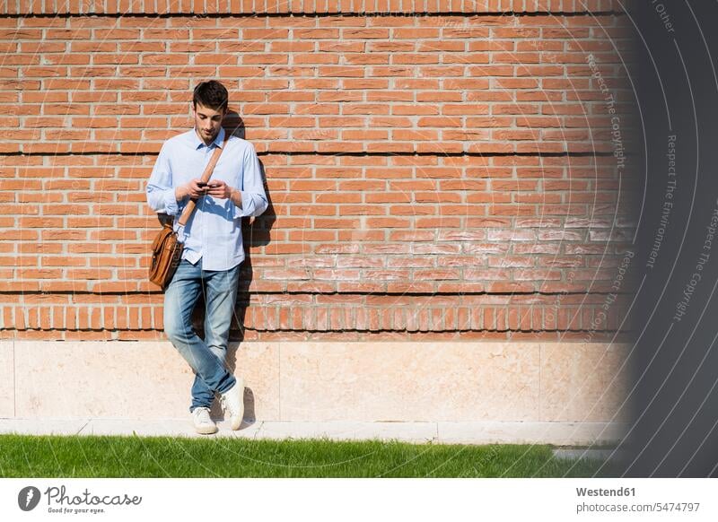 Young man using smartphone in the city shirts telecommunication phones telephone telephones cell phone cell phones Cellphone mobile mobile phones mobiles
