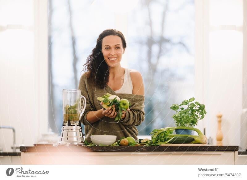 Fit woman standing in kitchen, preparing healthy smoothie human human being human beings humans person persons caucasian appearance caucasian ethnicity european