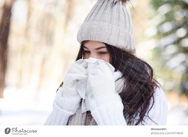 Young woman blowing nose in winter females women hibernal Adults grown-ups grownups adult people persons human being humans human beings honking caucasian