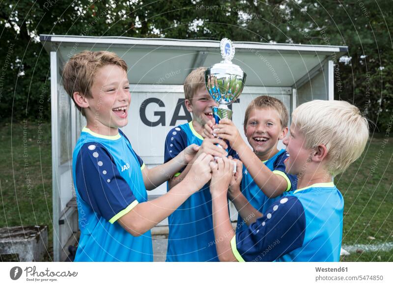 Young football players cheering with cup soccer boy boys males jubilate rejoicing rejoice exultation jubilating footballers soccer players cups trophy trophies