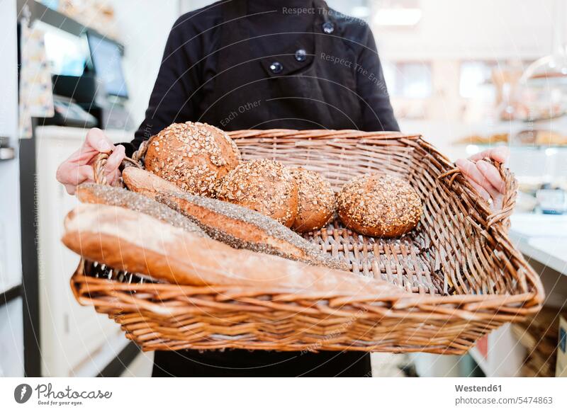 Female baker holding various breads in wicker basket at bakery color image colour image indoors indoor shot indoor shots interior interior view Interiors day