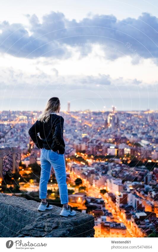 Rear view of young woman standing above the city at dawn, Barcelona, Spain human human being human beings humans person persons caucasian appearance