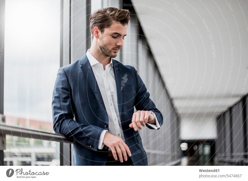 Businessman at the window checking the time wrist watch Wristwatch Wristwatches wrist watches Business man Businessmen Business men windows business people
