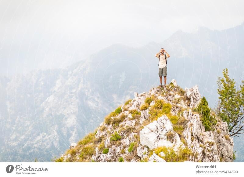 Italy, Massa, man standing on top of a peak in the Alpi Apuane mountains men males summit mountaintops summits mountain top mountain range mountain ranges