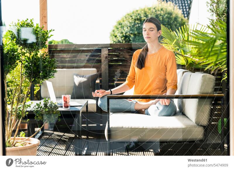 Young woman sitting on couch on terrace practicing yoga human human being human beings humans person persons caucasian appearance caucasian ethnicity european 1