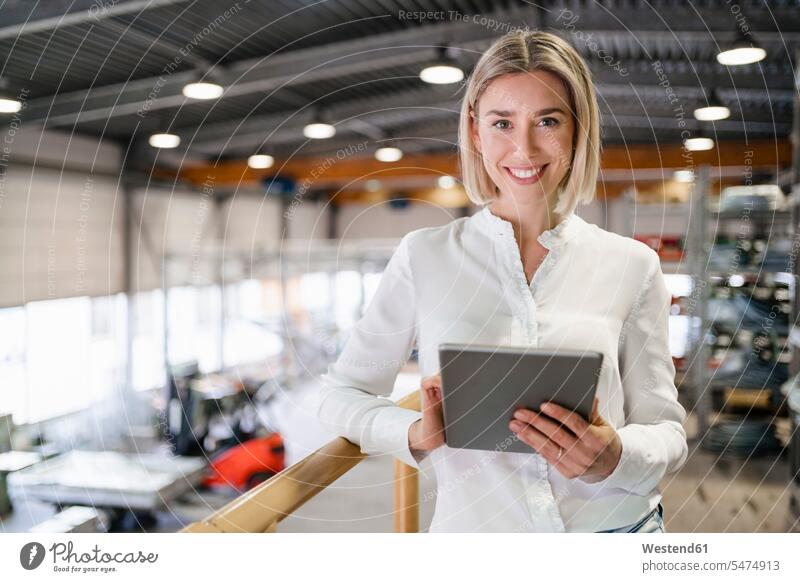 Portrait of smiling young woman using tablet in a factory human human being human beings humans person persons caucasian appearance caucasian ethnicity european