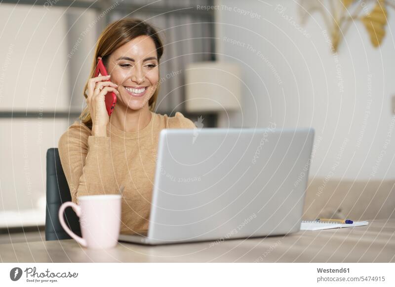 Businesswoman smiling while talking on phone at home color image colour image indoors indoor shot indoor shots interior interior view Interiors day