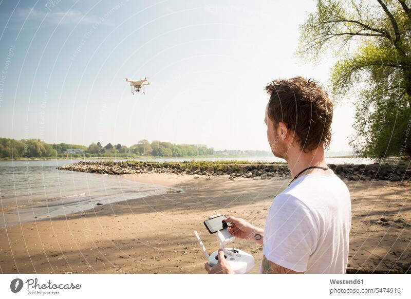 Man flying drone at a river River Rivers drones man men males water waters body of water Adults grown-ups grownups adult people persons human being humans